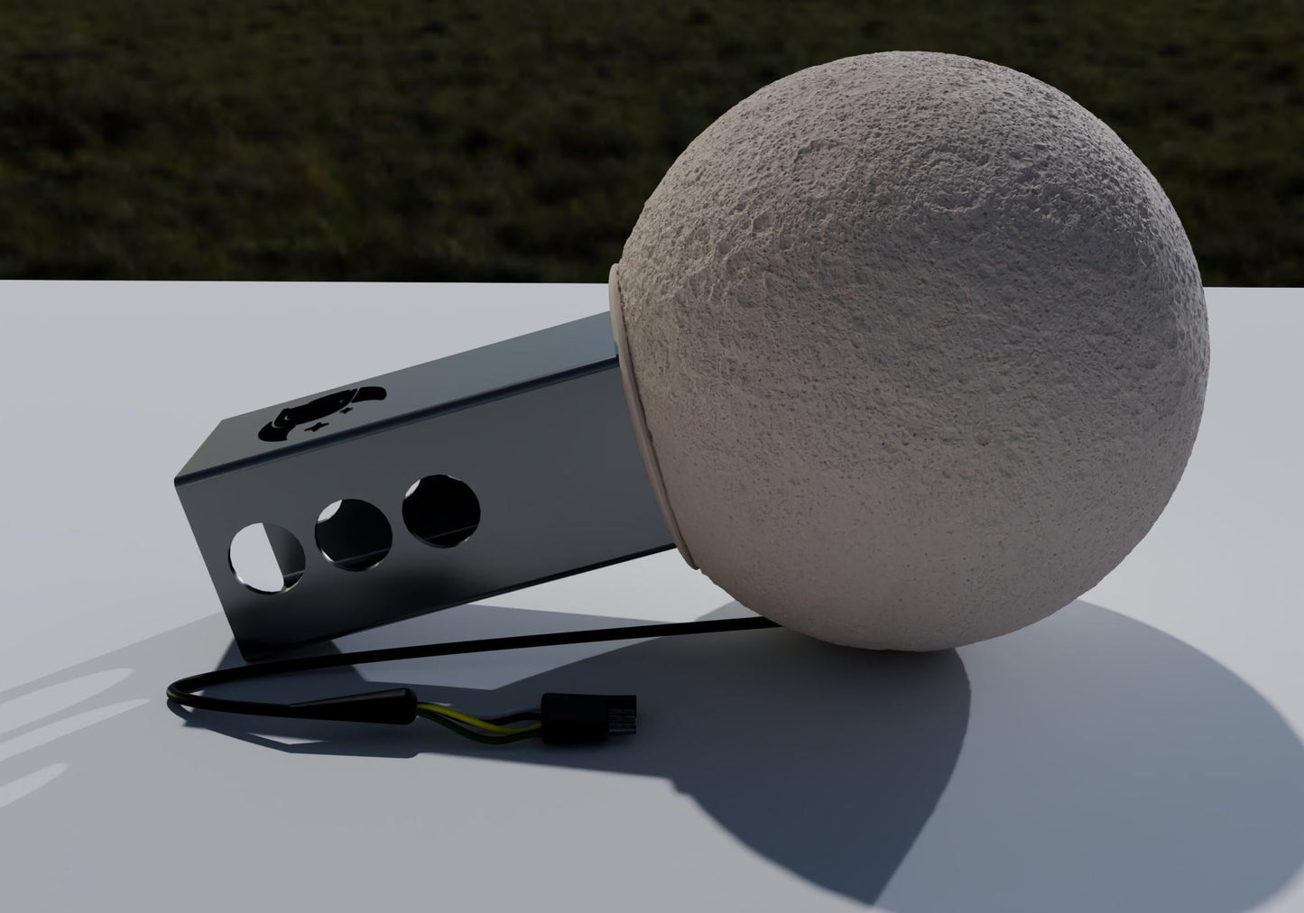 a large, round, white object resembling a ball or a sphere, placed on a white surface. There is a black wire or cable lying next to the object, and a small, rectangular object with three holes is also visible in the image.