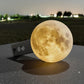 A large, glowing moon-shaped object rests on a dark surface, casting a shadow and illuminating the surrounding area.