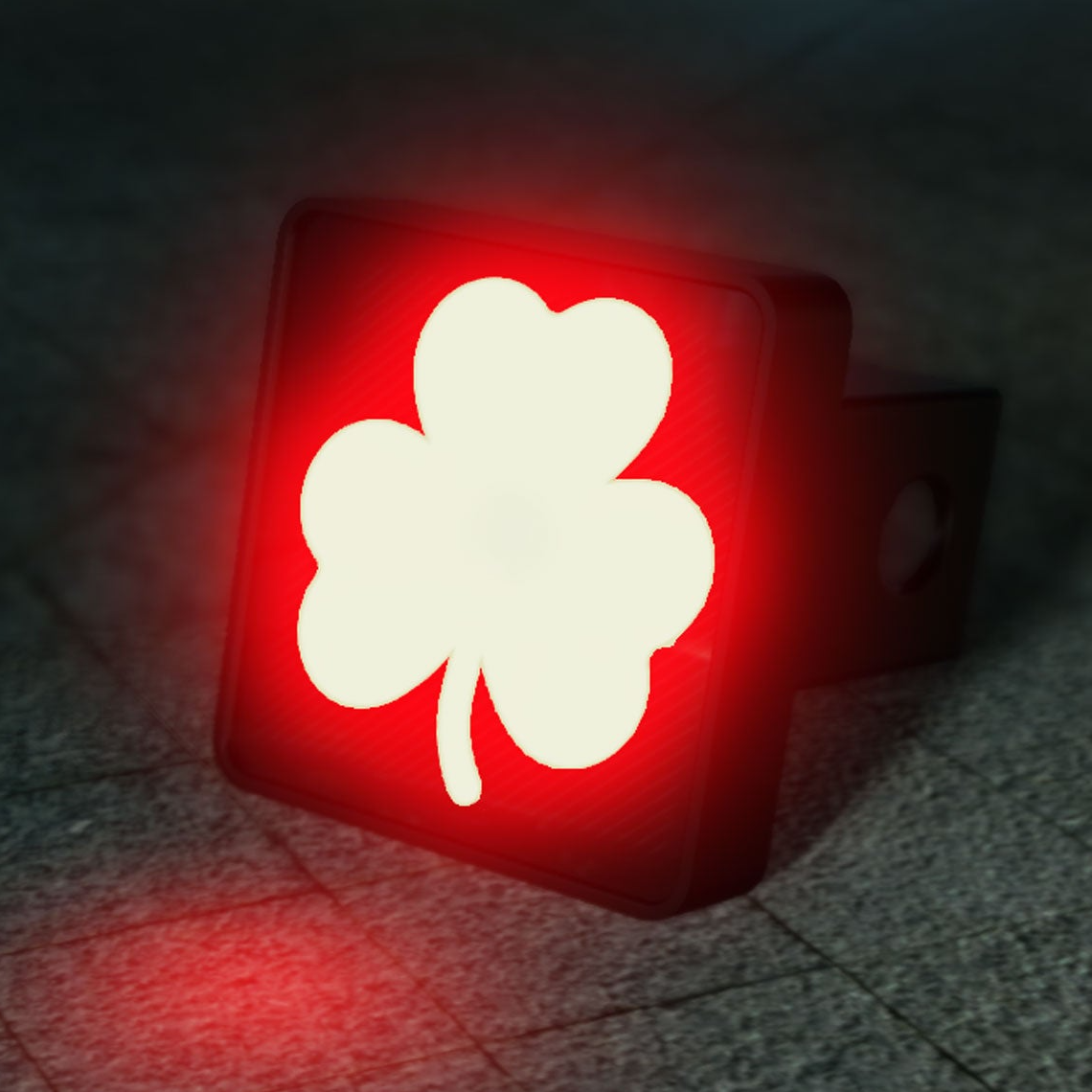 A red and white clover symbol is displayed on a trailer hitch, which is illuminated in the dark.