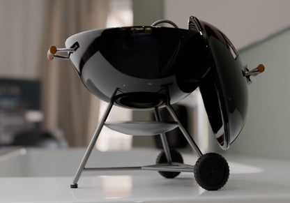 A sleek black grill with a black lid and silver legs is displayed on a white countertop.