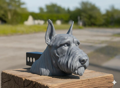 A gray ceramic dog head sculpture is displayed on a wooden post, with a blurred background of trees and a road.