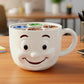 A white coffee mug with a smiling face design sits on a wooden desk, surrounded by various office supplies.