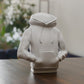 a white statue of a person sitting on a table