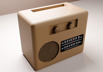 A tan-colored vintage radio with a speaker and two knobs, sitting on a white surface.