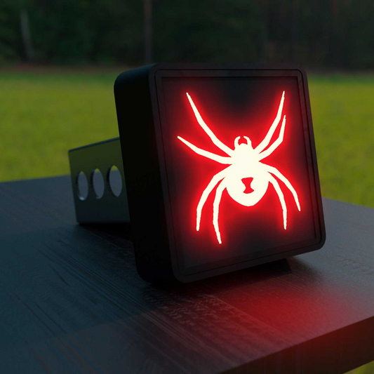 A red illuminated spider graphic is displayed on a black object, which appears to be a piece of electronic equipment or a small device.