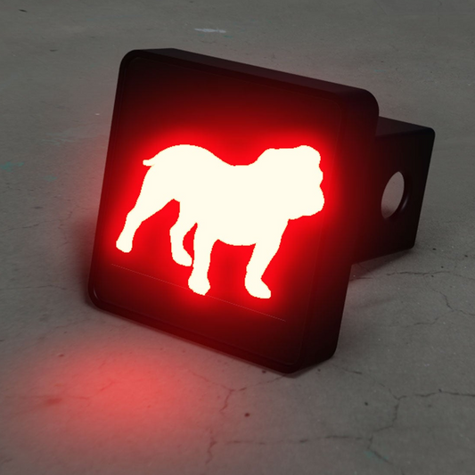 A red and white bulldog decal is displayed on a black trailer hitch, which is sitting on a concrete surface.