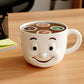 A white coffee mug with a smiling face design sits on a wooden desk, surrounded by various office supplies.