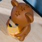 a brown bear figurine sitting on top of a wooden table