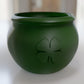 a green pot with a four leaf clover on it