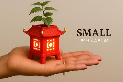 a hand holding a small red building with a plant growing out of it