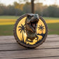 A dinosaur head sculpture is displayed on a wooden surface, with a palm tree silhouette and a yellow light behind it, creating a tropical ambiance.