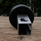 A black metal object with a silver logo is placed on a wooden surface.