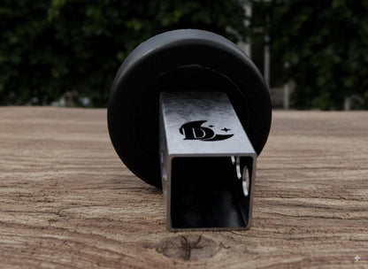 A black metal object with a silver logo is placed on a wooden surface.