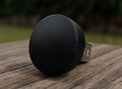 A black object is resting on a wooden surface, with a blurred background.