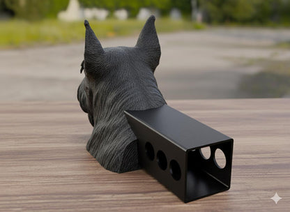 A black dog statue is sitting on a wooden surface, with a black rectangular object attached to its back.