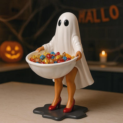 A Halloween-themed statue of a ghost holding a bowl of candy, with a carved jack-o-lantern in the background.