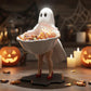 A Halloween-themed scene featuring a ghost figurine holding a bowl of candy, surrounded by carved pumpkins, lit candles, and spiderwebs.