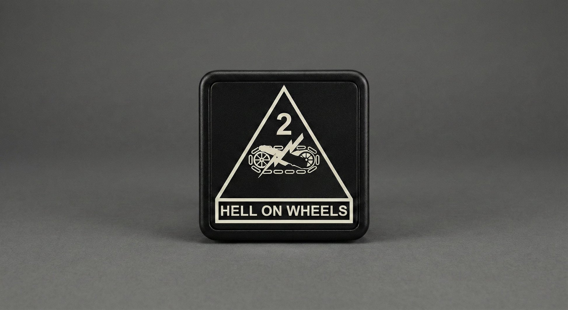 A black square sign with a white triangle and text on it, placed on a gray background.