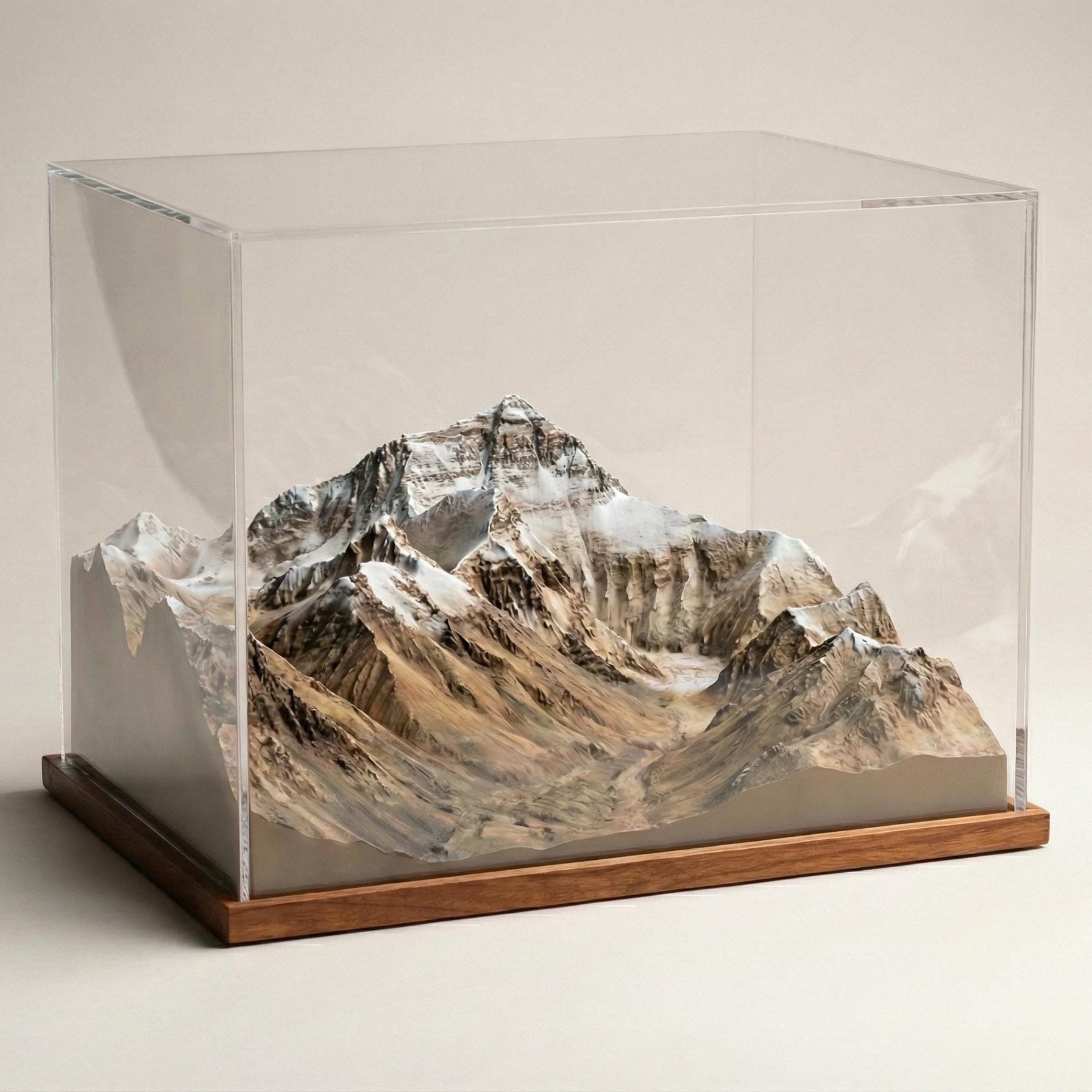 A glass display case containing a miniature model of a mountain range, with the peaks and valleys clearly visible.
