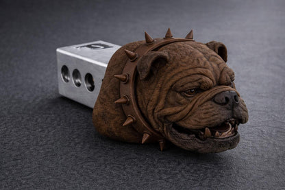 A brown bulldog head with spikes protruding from its mouth is resting on a gray surface.