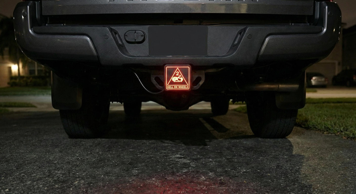 the rear of a black pickup truck with a red warning light on the tailgate.