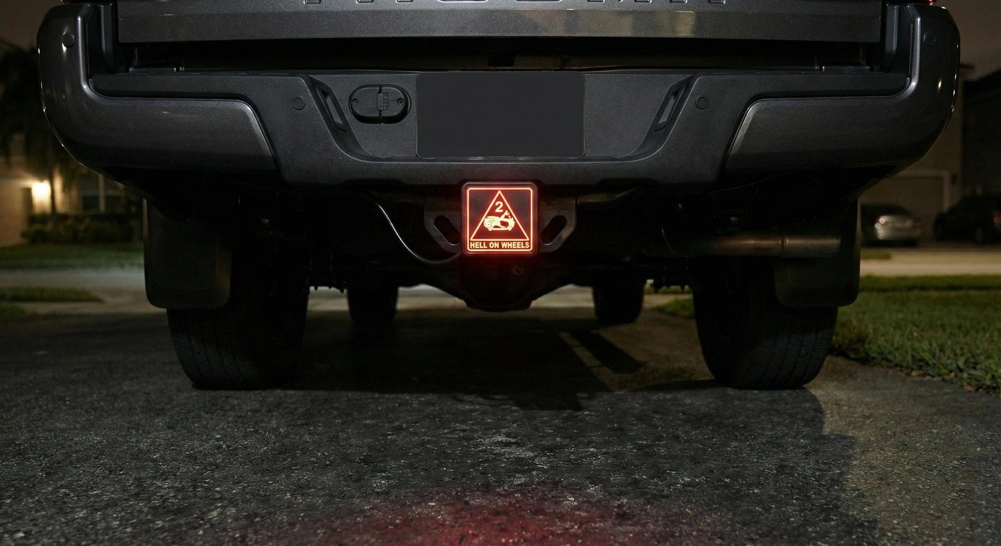 the rear of a black pickup truck with a red warning light on the tailgate.