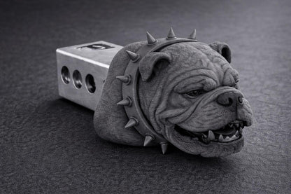 A close-up black and white image of a dog head with spikes on its collar, sitting on a dark surface.